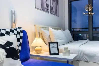 a room with a bed and a table with a lamp at Affordable Staycation with Balcony at The Gramercy Makati in Manila