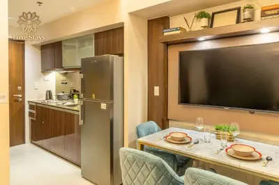 a kitchen and dining room with a table and a large television at Luxurious 1BR Staycation at One Uptown BGC in Manila
