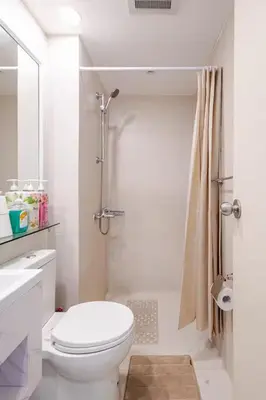 a white bathroom with a toilet and a shower at Dsa'sCrib 1BR Azure Near Airport in Manila