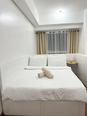a white bed with a pillow on top of it at 1bedroom LOFT with Garden Terrace pool access in Manila