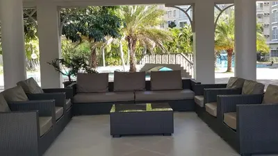 a living room with a couch and tables and palm trees at Emjay's staycation in Manila
