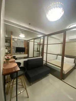 a room with a bed and a desk and a table at Lush Suite Makati in Manila