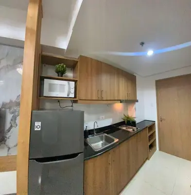 a kitchen with a stainless steel refrigerator and wooden cabinets at Lush Suite Makati in Manila
