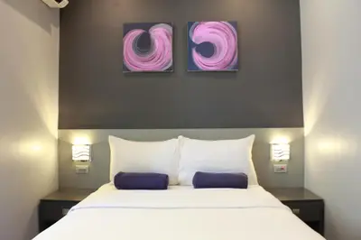 a bedroom with a large bed with two paintings on the wall at Leez Inn Malate in Manila