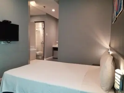 a bedroom with a white bed and a television at Leez Inn Malate in Manila