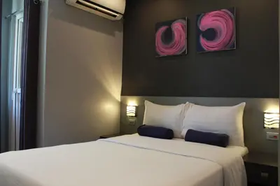 a bedroom with a large bed with two paintings on the wall at Leez Inn Malate in Manila
