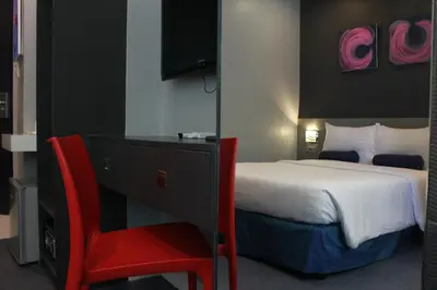 a hotel room with a bed and a red chair at Leez Inn Malate in Manila