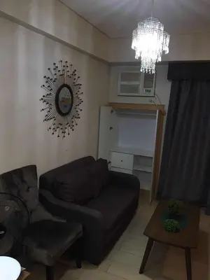 a living room with a couch and a clock on the wall at Infinity Stay in Manila