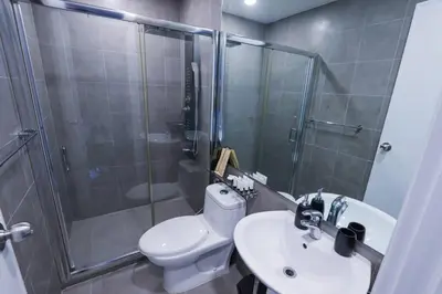 a bathroom with a shower and a toilet and a sink at Spacious and Cozy 2 Br in The Gramercy Poblacion in Manila