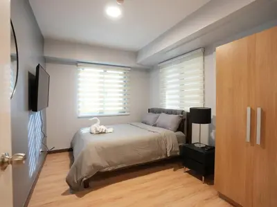 a bedroom with a bed with a television and a window at High Floor 2BR in Knightsbridge Residences Makati in Manila