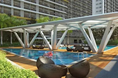 a swimming pool with chairs and a large building at Cozy 2BR Unit in FAME Residences, Mandaluyong City in Manila