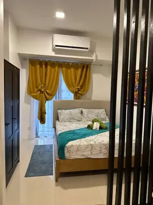 a bedroom with a bed with a fan and a window at Cozy 2BR Unit in FAME Residences, Mandaluyong City in Manila