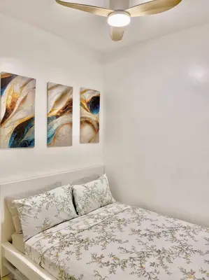 a bedroom with four paintings on the wall at Cozy 2BR Unit in FAME Residences, Mandaluyong City in Manila