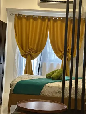 a bedroom with a bed with yellow curtains and a window at Cozy 2BR Unit in FAME Residences, Mandaluyong City in Manila