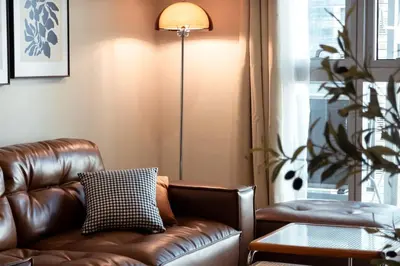 a brown leather couch in a living room with a lamp at Parksuites BGC - Spacious 2 Bedroom in Manila