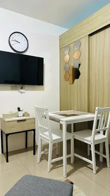 a dining room with a table and two chairs and a clock at Homey Staycation at MOA Complex in Manila