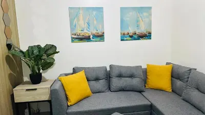 a living room with a gray couch with yellow pillows at Homey Staycation at MOA Complex in Manila