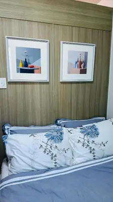 a bedroom with a bed with two pictures on the wall at Homey Staycation at MOA Complex in Manila