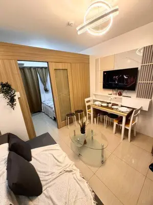 a living room with a bed and a dining room at Daisy's Suite by Staycation in Manila
