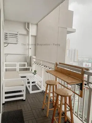 a room with a table and stools on a balcony at 2BR The Blums at Prisma Residences in Manila