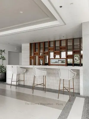 a kitchen with three white chairs and a counter at 2BR The Blums at Prisma Residences in Manila