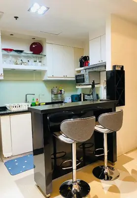 a kitchen with two bar stools in front of a counter at BEAUTIFUL and SPACIOUS 2 REAL BEDROOMS 2 BATHROOMS IN BGC GLOBAL CITY in Manila