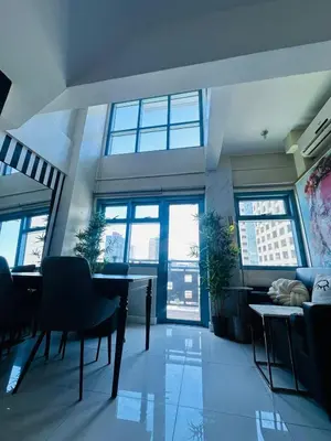 a room with a table and chairs and windows at Newly Renovated 2-storey Loft at Greenbelt 1 in Manila