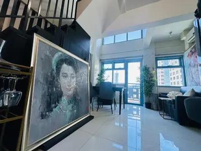 a living room with a large painting of a woman at Newly Renovated 2-storey Loft at Greenbelt 1 in Manila