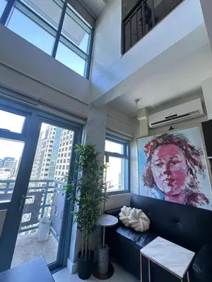 a living room with a couch and a large painting at Newly Renovated 2-storey Loft at Greenbelt 1 in Manila