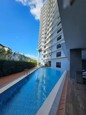 a swimming pool next to a tall building at Happy Haven at Lush Makati in Manila