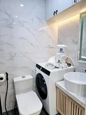 a bathroom with a washing machine and a sink at Alexa Smart Home l Balcony Night View l Fast Wifi in Manila