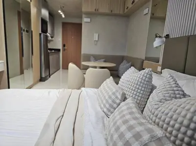 a bedroom with a bed with pillows and a table at Alexa Smart Home l Balcony Night View l Fast Wifi in Manila