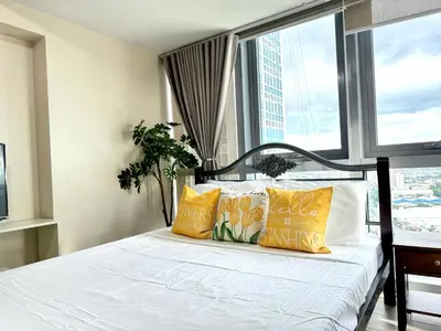 a bedroom with a bed with yellow pillows and a window at Eastwood Global Plaza Luxury 1Bed Room with 2 Toilets and Laundry Room in Manila