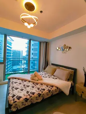 a bedroom with a bed with a large window at CHILL City Escapes at Azure Urban Residences in Manila