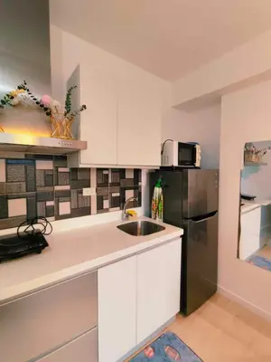 a kitchen with white cabinets and a stainless steel refrigerator at CHILL City Escapes at Azure Urban Residences in Manila