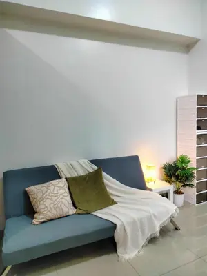 a blue couch with a blanket on it in a room at SMDC StayWise Space in Manila