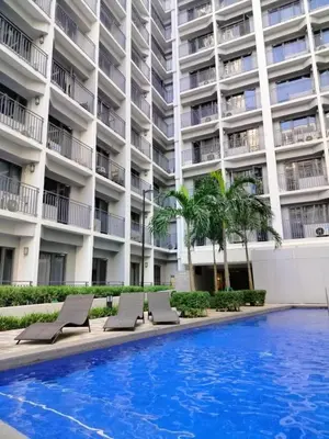 a hotel swimming pool with lounge chairs in front of a building at SMDC StayWise Space in Manila
