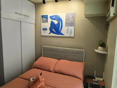 a small bedroom with a bed with orange sheets at Condominium in Manila