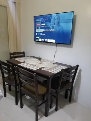 a dining room table with chairs and a television on a wall at Sea residence Family Group Affordable staycation in Manila