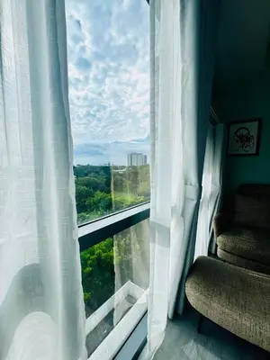 a window with white curtains and a chair in a room at Enter Home McKinley with a View in Manila