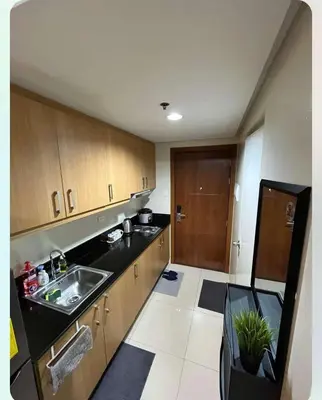 a kitchen with wooden cabinets and a sink in it at Adrianne Condotel at Shell Residences Condominium, MOA Complex, Pasay City in Manila
