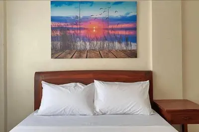 a bed with white pillows and a painting on the wall at Lawton Residences Studio Room 3E in Manila