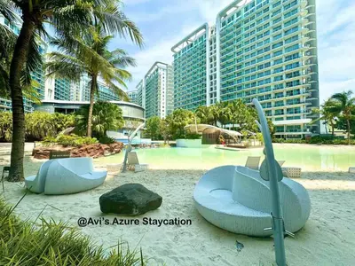 a beach with two blue chairs and some buildings at Azure Urban Resort Residences in Manila