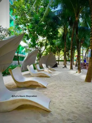 a row of lounge chairs on a beach with palm trees at Azure Urban Resort Residences in Manila