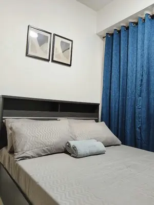 a bedroom with a bed with blue curtains at Shore Residences - 1 Bedroom Condo Unit in Manila