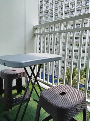 a table and stool on a balcony with a building at Shore Residences - 1 Bedroom Condo Unit in Manila