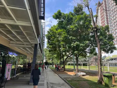 a woman walking down a sidewalk next to a building at Heart of Ortigas Center in Manila
