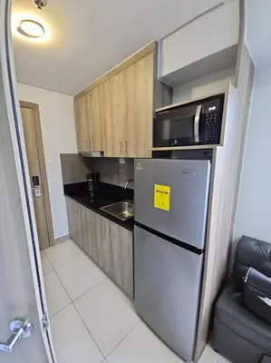 a small kitchen with a refrigerator and a microwave at Condo next door in Manila