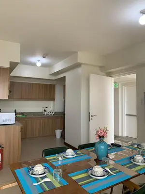 a dining room with a table and a kitchen at Fairlane Residences in Manila