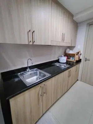 a kitchen with a sink and wooden cabinets at Near MOA at SHORE RESIDENCES 1BR with balcony -unlimited WIFI in Manila